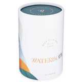 A white paperboard tube with gold text, and a sea green, blue, and copper foil design sits against a white backdrop. The product is Deep Blue Sea Bath Soak by Waterbody