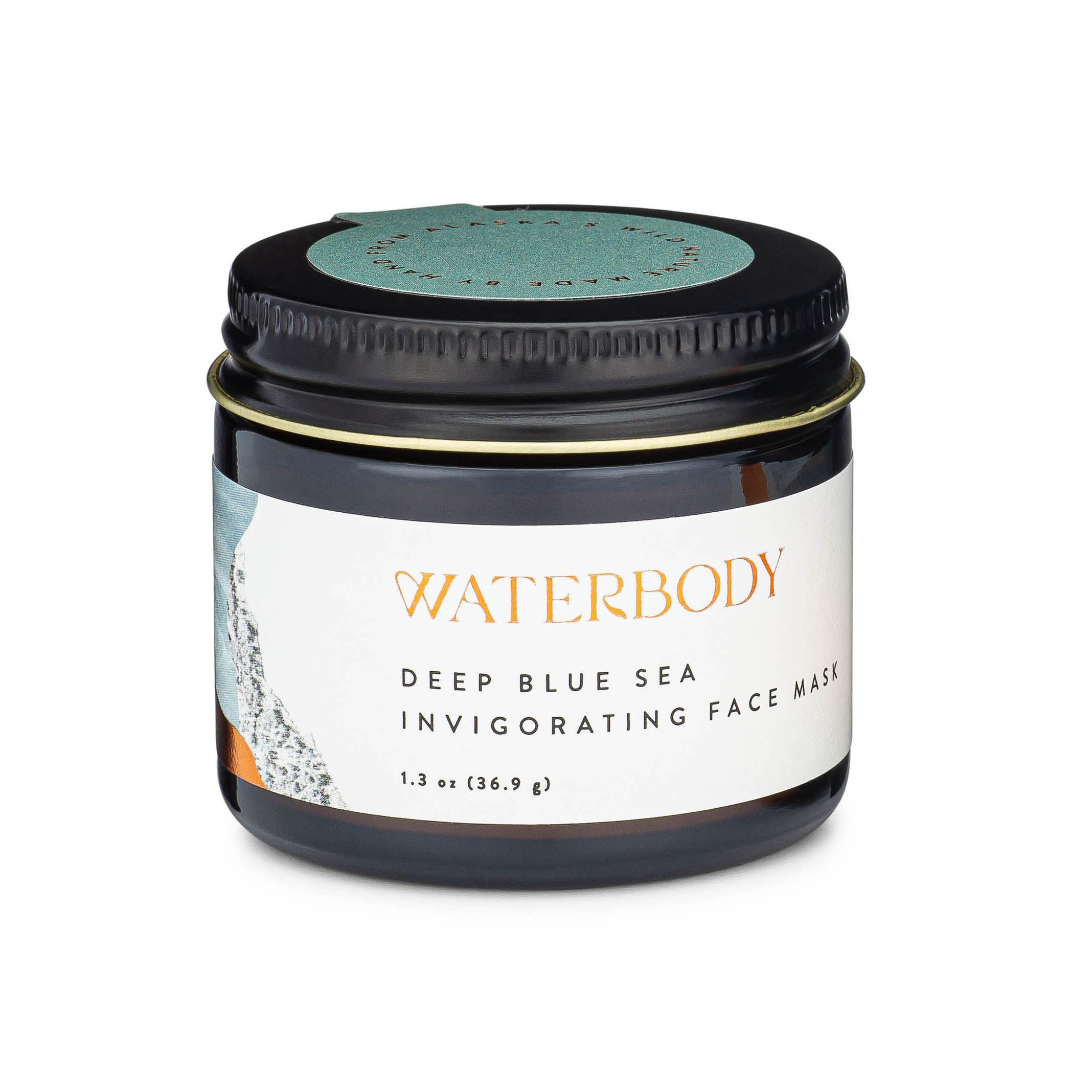 A brown glass jar with a black tin lid has a white label with gold foil text displaying Waterbody Deep Blue Sea Invigorating Face Mask