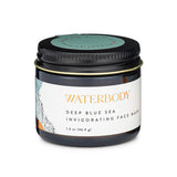 A brown glass jar with a black tin lid has a white label with gold foil text displaying Waterbody Deep Blue Sea Invigorating Face Mask