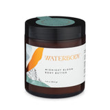 A brown glass jar with black lid and green sticker seal, white label with green and gold accents reads "Waterbody Midnight Bloom Body Butter". the background is white