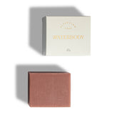 Waterbody Alpenglow pink clay soap bar on a white background beside white and gold cardboard box packaging